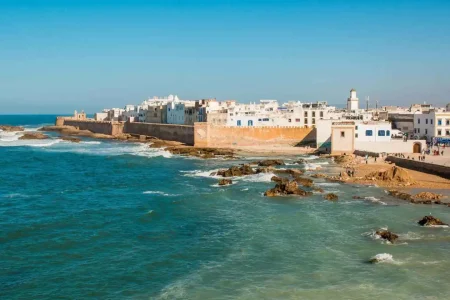 Image displaying a breathtaking moment on an Essaouira day trip, with golden sands meeting the clear blue sea under a radiant sun, encapsulating the serene beauty and charm of the location