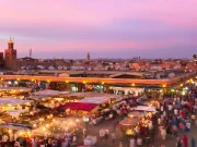 2 day trips from marrakech to merzouga : A panoramic view featuring a caravan of camels trekking towards the golden dunes of the 2 day trips from marrakech to merzouga at sunset, with the majestic Atlas Mountains in the background