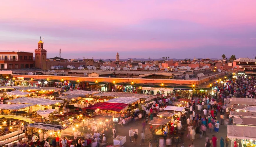 2 Day Trips From Marrakech to Merzouga 18 2 day trips from marrakech to merzouga : A panoramic view featuring a caravan of camels trekking towards the golden dunes of the 2 day trips from marrakech to merzouga at sunset, with the majestic Atlas Mountains in the background