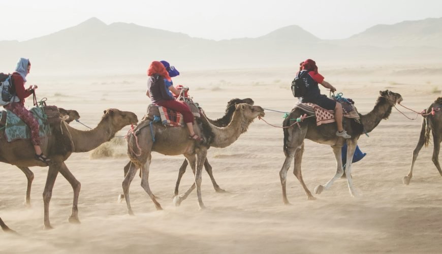 Let's Enjoy Morocco Tours: Best Time to Visit and Must-See Places 14 group of people riding camel on sand dune in morocco tours